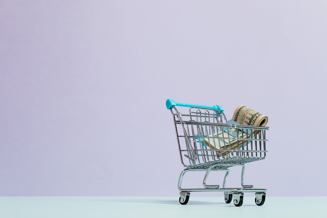 The Art of Drawing Readers In: Your attractive post title goes here A close-up of a mini shopping cart with rolled cash on a pastel background. Ideal for finance and ecommerce themes.